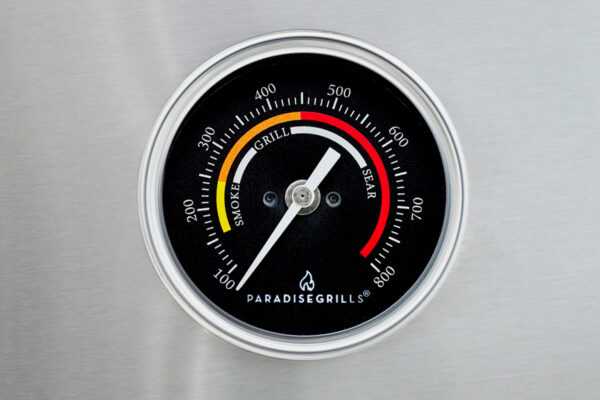 Close-up of a Grill tempature gauge against a stainless steel background, indicating temperatures in both fahrenheit and zones labeled as smoke, grill, and sear.