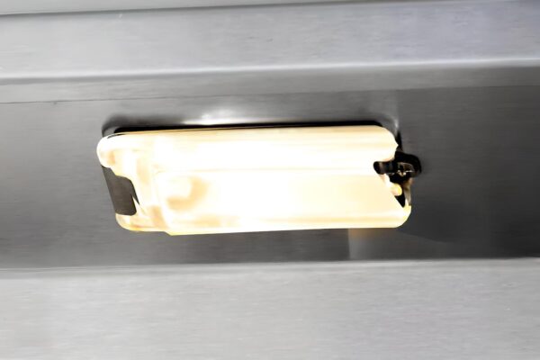 A close-up of a grill interior lights, plastic handle attached to it, and shadows around the edges