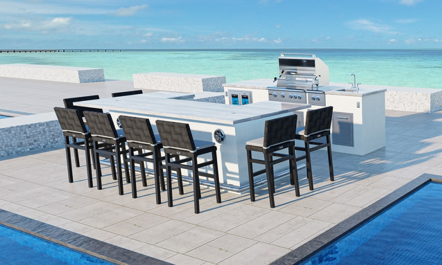 Experience the MAUI 10 + GX10 outdoor kitchen and dining area, featuring a sleek modern grill, sink, and ample storage space. Enjoy meals at the long bar-style table adorned with eight stylish black high chairs. This exquisite setting offers stunning views of a blue ocean and clear sky, with a pool in the foreground and a pier in the background.